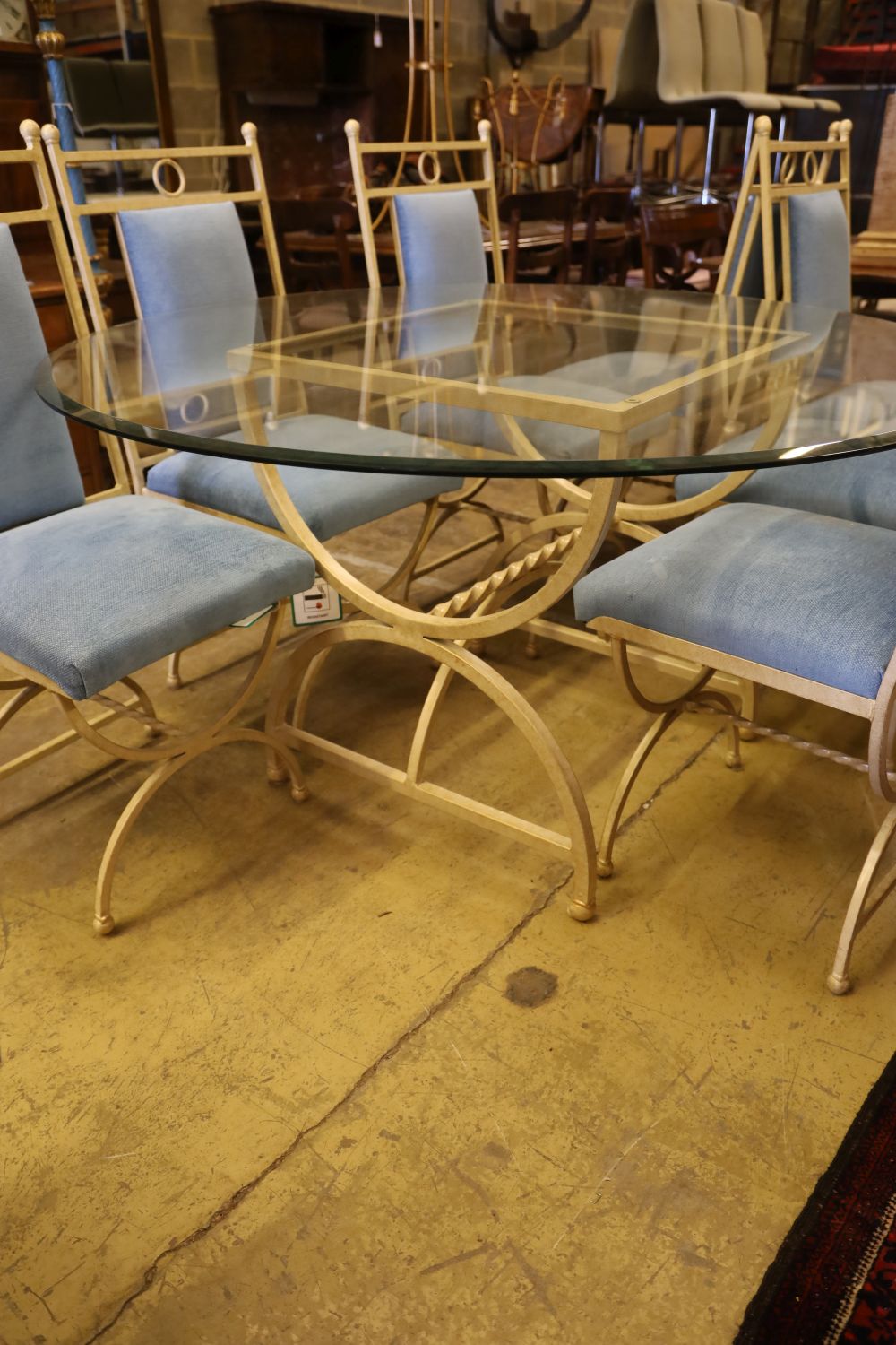 An enamelled metal dining suite comprising a circular glass-topped table and a set of eight chairs, table 138cm diameter